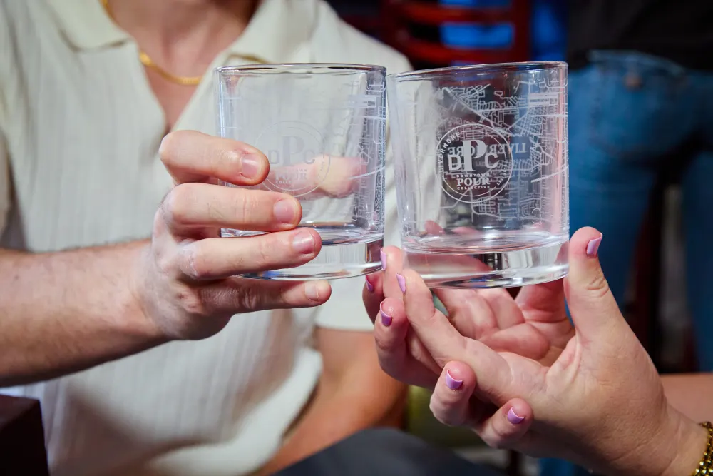 Two hands holding etched DPC rocks glasses